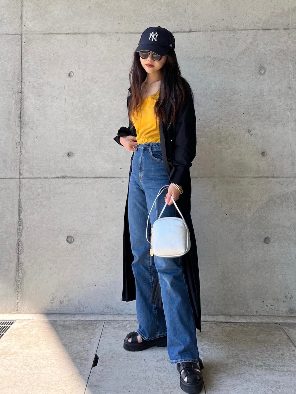 ブラック系のワンピース、イエロー系のタンクトップ、ブルー系のデニムパンツを着用したレディースの春コーディネートの2枚目の写真