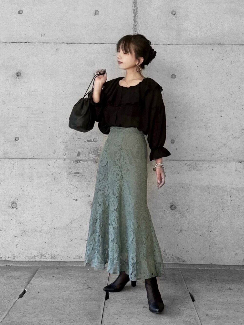 ブラック系のシャツ/ブラウス、グリーン系のスカート、ブラック系のサンダルを着用したレディースの春コーディネートの2枚目の写真