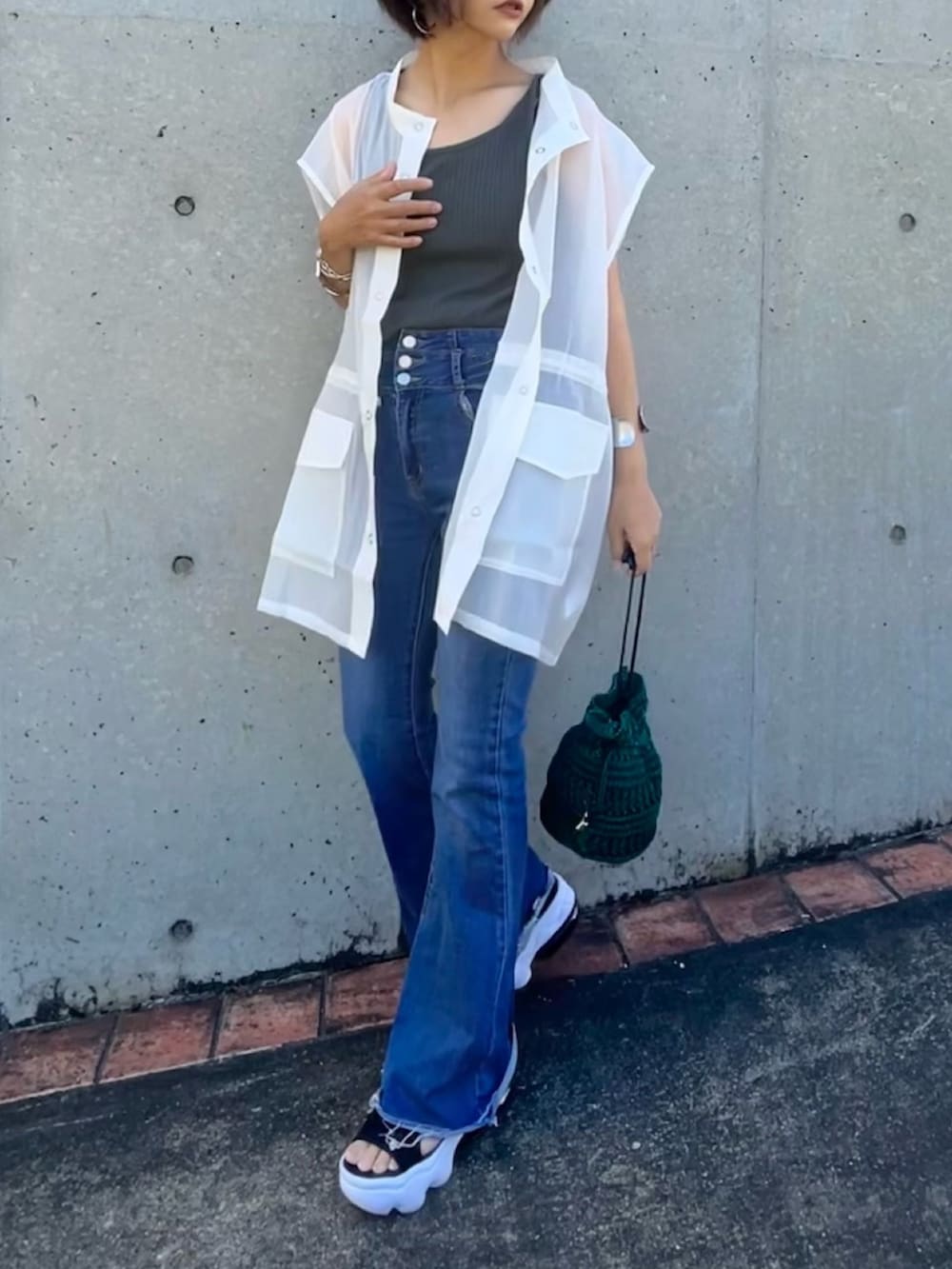 ホワイト系のベスト、ブルー系のデニムパンツ、グリーン系のタンクトップを着用したレディースの夏コーディネートの2枚目の写真