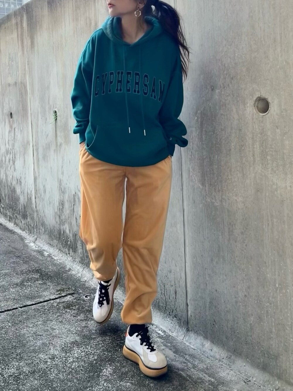 グリーン系のパーカー、ベージュ系のその他パンツ、ホワイト系のスニーカーを着用したレディースの冬コーディネートの2枚目の写真