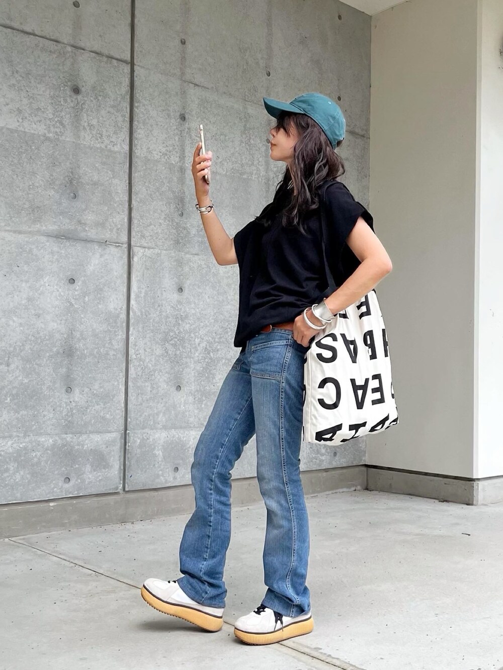 ブラック系のTシャツ/カットソー、ブルー系のデニムパンツ、ホワイト系のスニーカーを着用したレディースの夏コーディネートの2枚目の写真