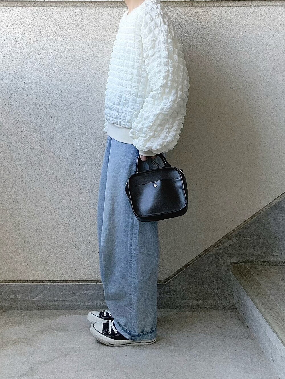 ホワイト系のTシャツ/カットソー、ブルー系のデニムパンツ、ブラック系のスニーカーを着用したレディースの冬コーディネートの4枚目の写真