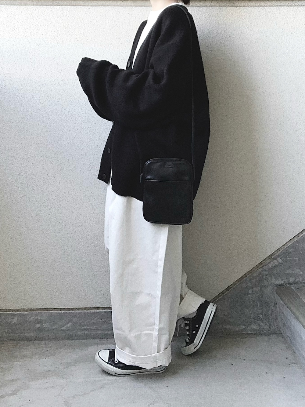 ベージュ系のチノパンツ、ブラック系のカーディガン/ボレロ、ホワイト系のTシャツ/カットソーを着用したレディースの秋コーディネートの2枚目の写真