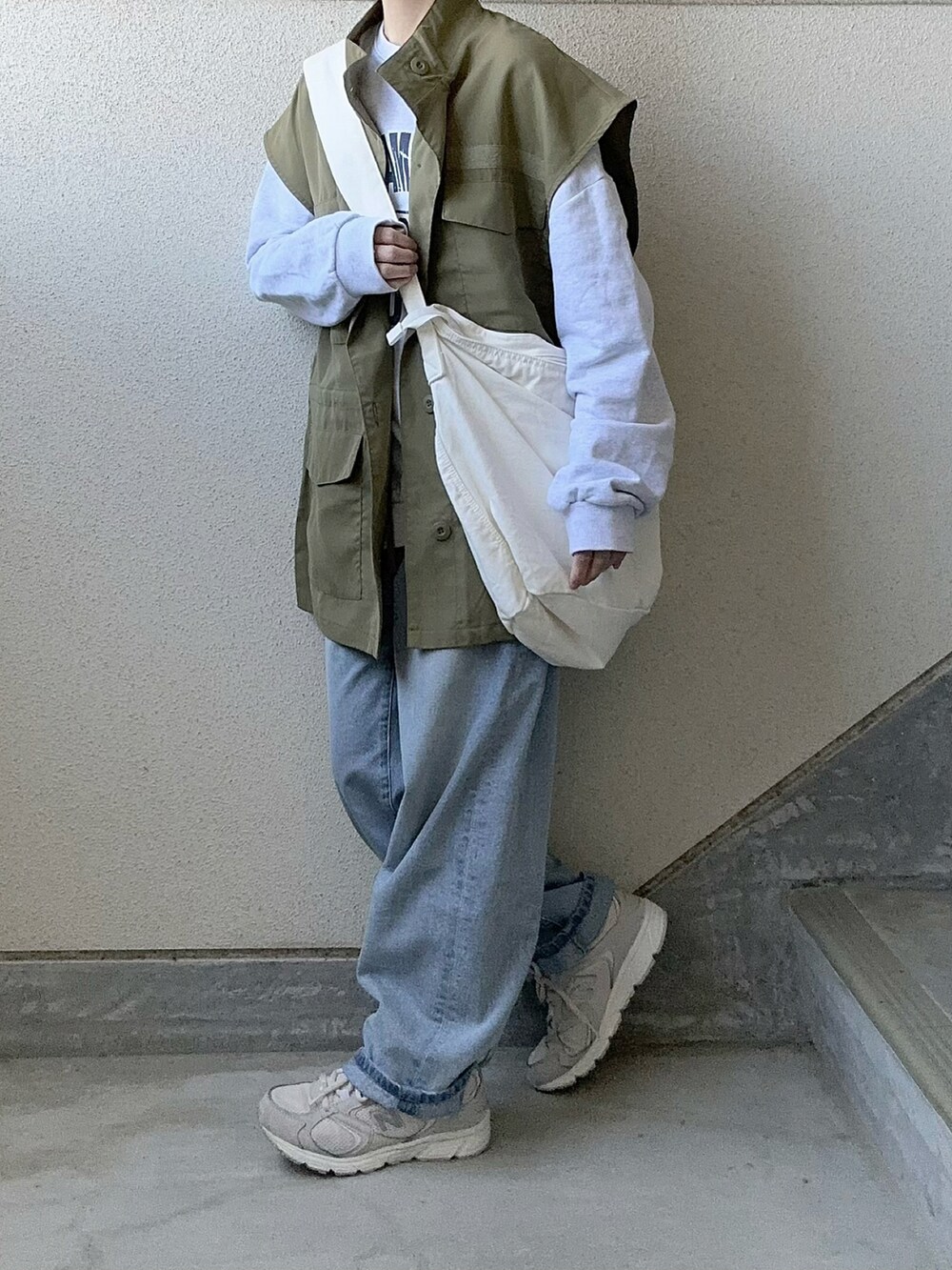 グリーン系のベスト、ブルー系のデニムパンツ、ホワイト系のショルダーバッグを着用したレディースの春コーディネートの5枚目の写真