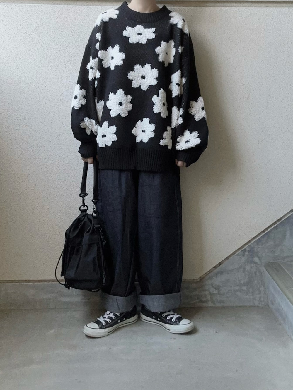 ブラック系のニット/セーター、ブルー系のデニムパンツ、ブラック系のショルダーバッグを着用したレディースの秋コーディネートの2枚目の写真