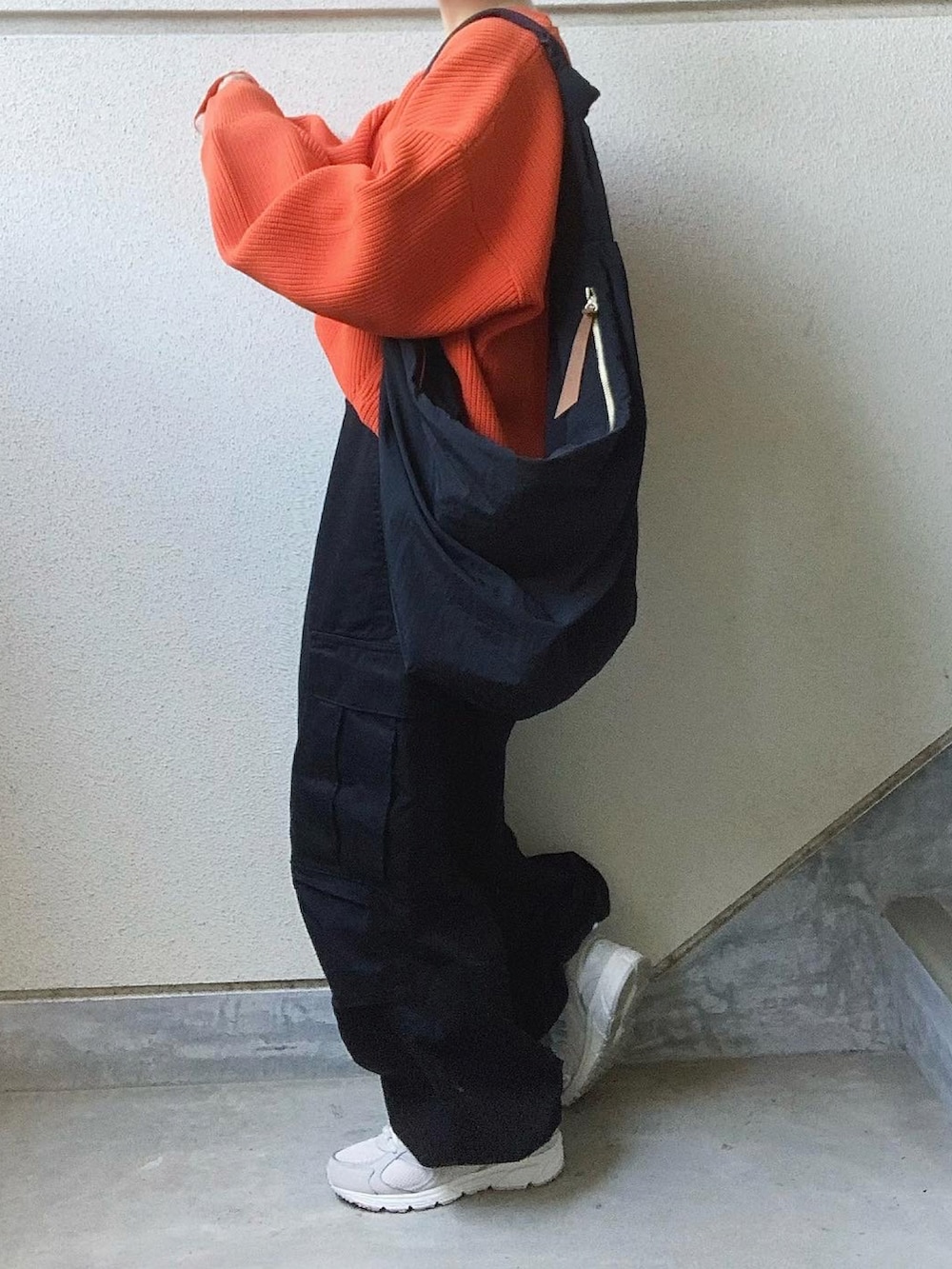 オレンジ系のニット/セーター、ブラック系のカーゴパンツ、グレー系のスニーカーを着用したレディースの秋コーディネートの2枚目の写真