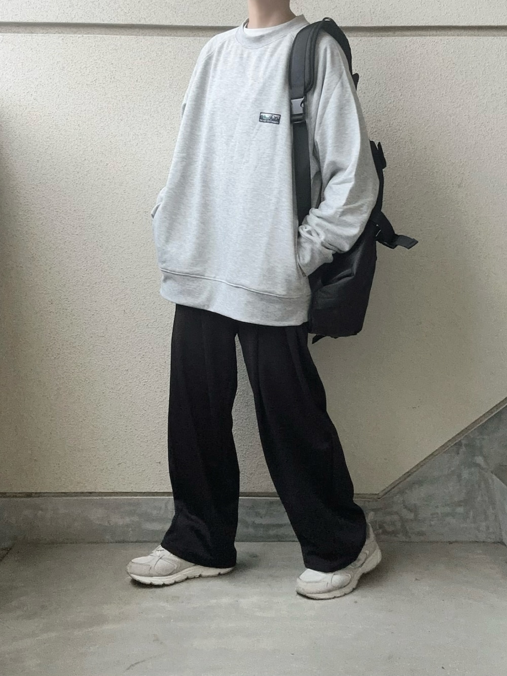 グレー系のスウェット、ブラック系のボディバッグ/ウエストポーチ、ブラック系のスラックスを着用したレディースの冬コーディネートの2枚目の写真