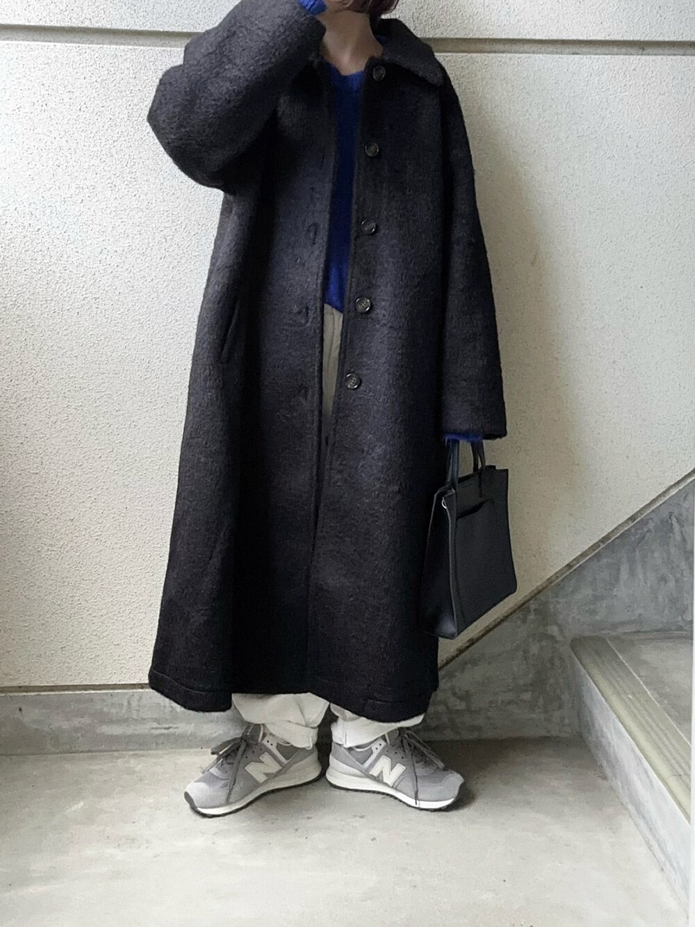ブラック系のチェスターコート、ブルー系のニット/セーター、ブラック系のショルダーバッグを着用したレディースの秋コーディネートの3枚目の写真