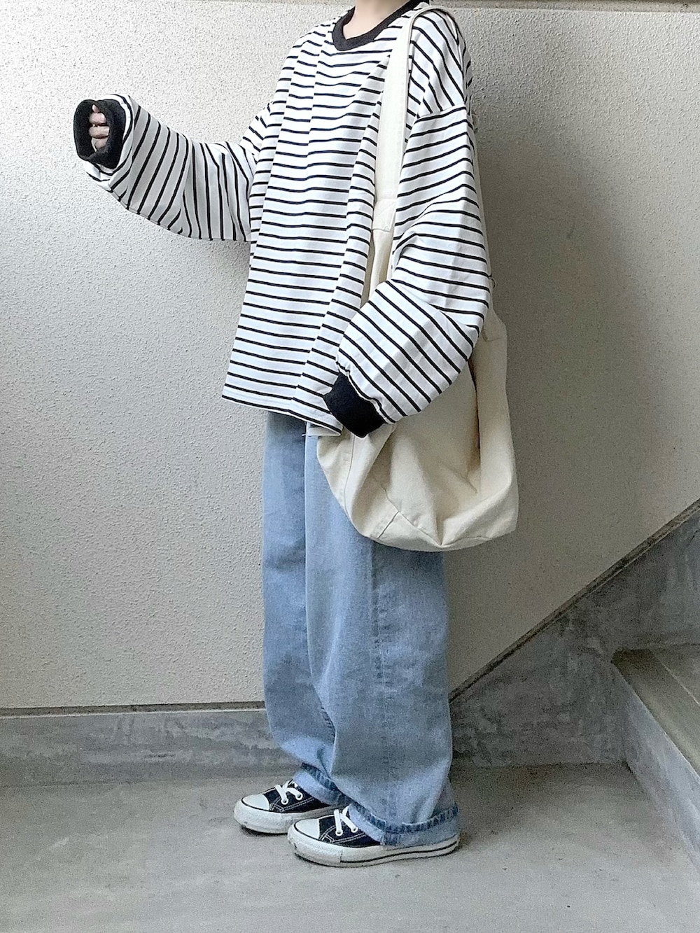 ブラック系のTシャツ/カットソー、ブルー系のデニムパンツ、ホワイト系のショルダーバッグを着用したレディースの春コーディネートの5枚目の写真