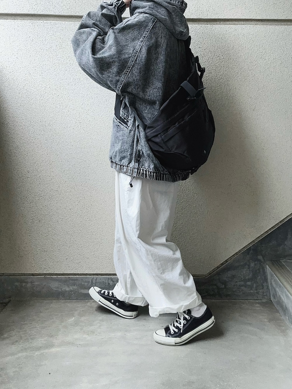 ブラック系のブルゾン、ブラック系のボディバッグ/ウエストポーチ、ホワイト系のチノパンツを着用したレディースの春コーディネートの3枚目の写真