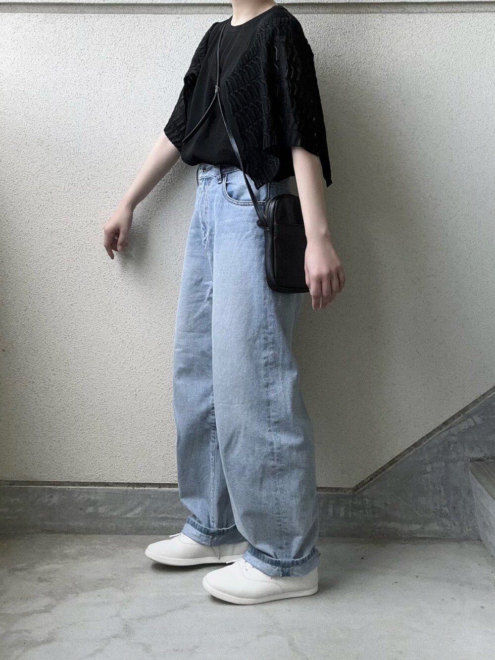 ブラック系のTシャツ/カットソー、ブルー系のデニムパンツ、ホワイト系のスニーカーを着用したレディースの春コーディネートの2枚目の写真