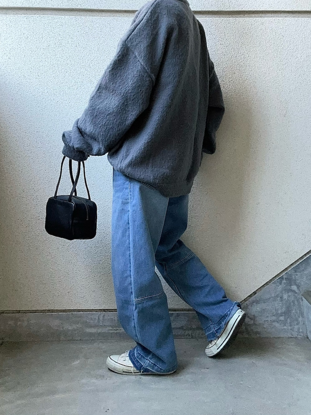 グレー系のニット/セーター、ブルー系のデニムパンツ、ブラック系のボストンバッグを着用したレディースの冬コーディネートの2枚目の写真