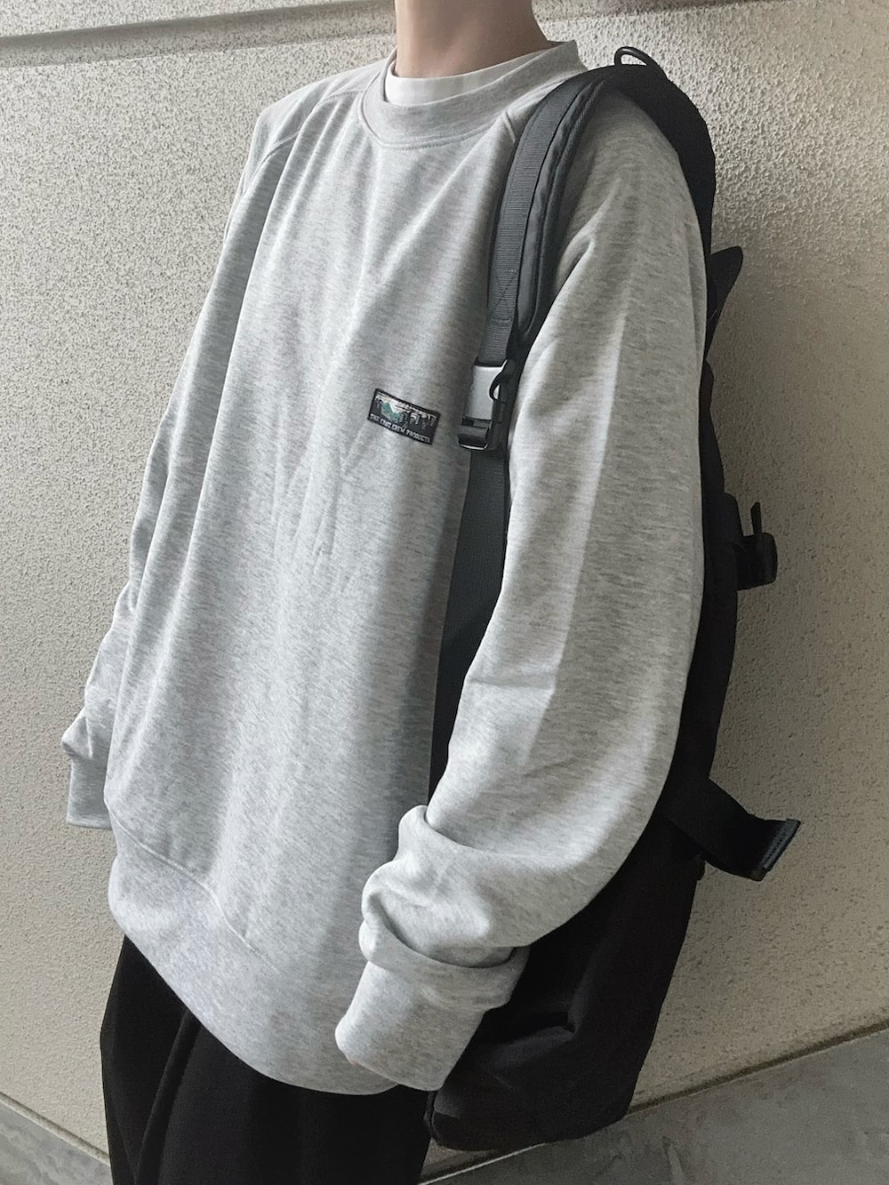 グレー系のスウェット、ブラック系のボディバッグ/ウエストポーチ、ブラック系のスラックスを着用したレディースの冬コーディネートの4枚目の写真