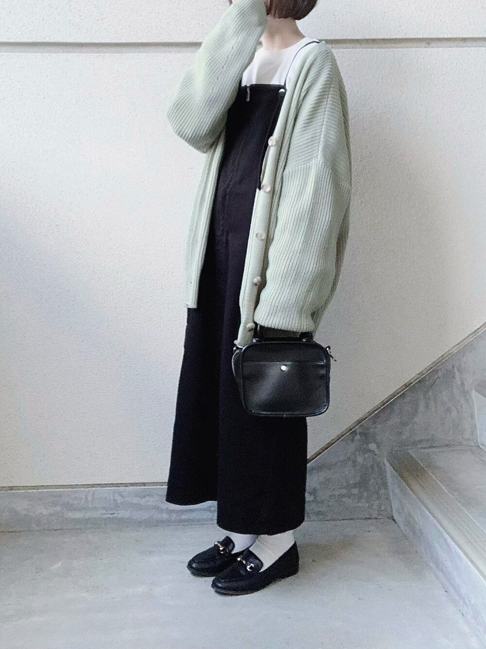 ブラック系のワンピース、グリーン系のカーディガン/ボレロ、ブラック系のトートバッグを着用したレディースの冬コーディネートの3枚目の写真