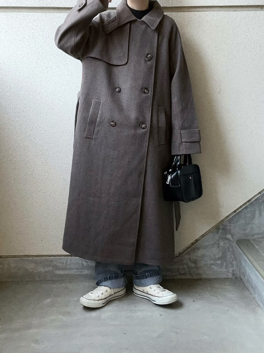 ブラウン系のチェスターコート、ブルー系のデニムパンツを着用したレディースの秋コーディネートの4枚目の写真