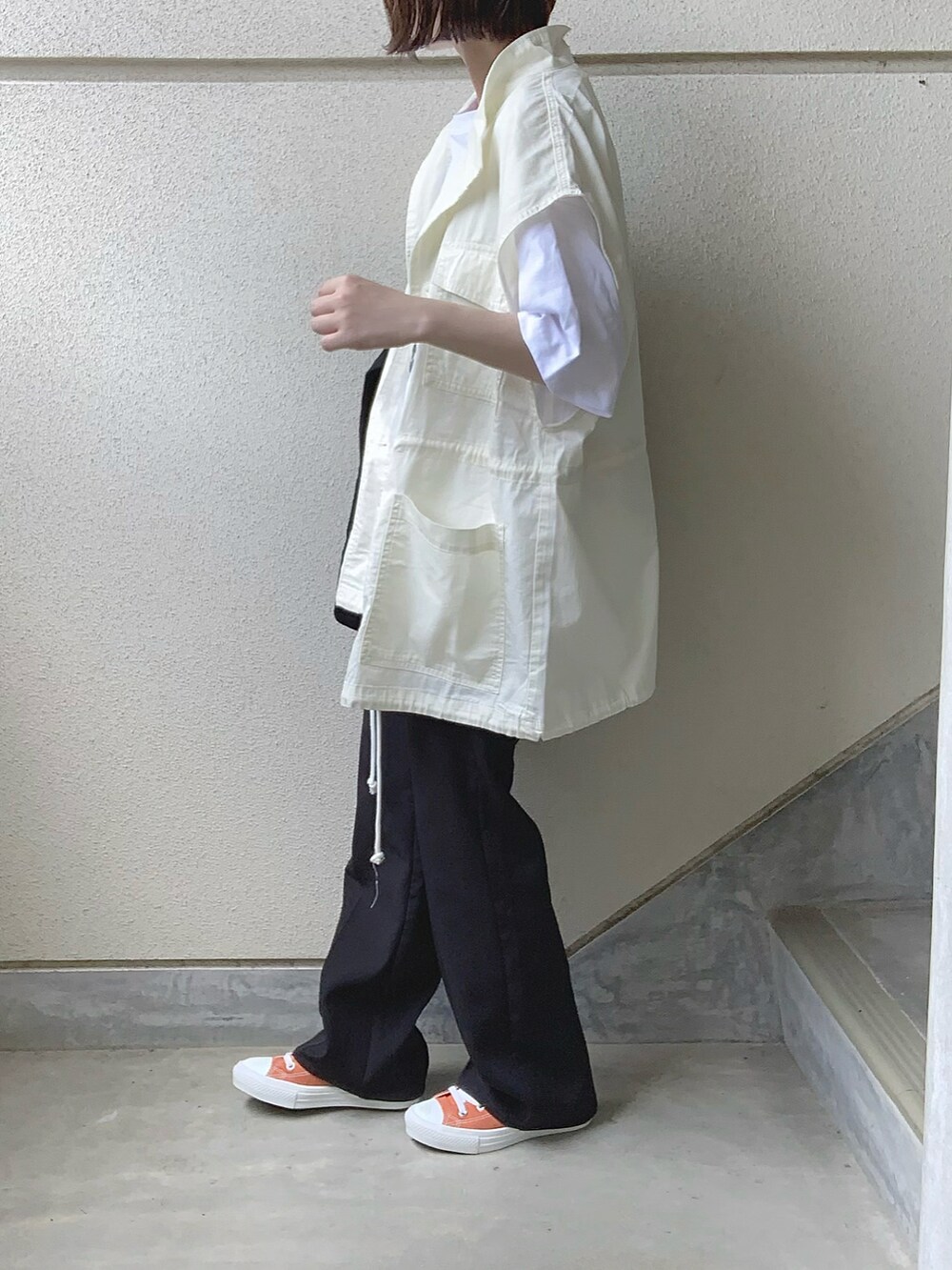 ホワイト系のベスト、ブラック系のスラックス、グレー系のTシャツ/カットソーを着用したレディースの夏コーディネートの2枚目の写真