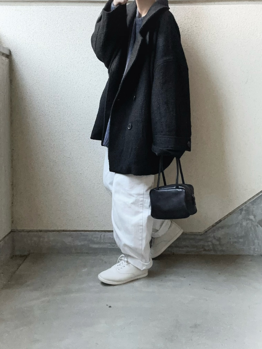 ブラック系のピーコート、ブラック系のボストンバッグ、ブルー系のニット/セーターを着用したレディースの冬コーディネートの3枚目の写真