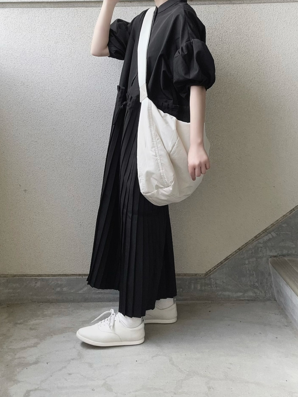ブラック系のワンピース、ホワイト系のショルダーバッグ、ホワイト系のスニーカーを着用したレディースの春コーディネートの2枚目の写真