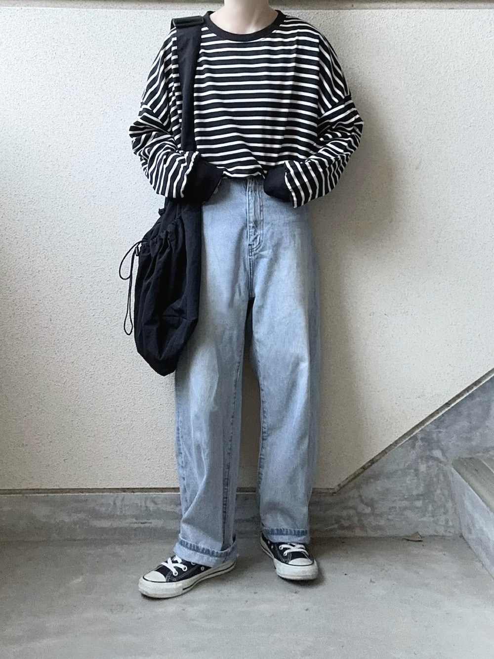 ブラック系のTシャツ/カットソー、ブラック系のショルダーバッグ、ブルー系のデニムパンツを着用したレディースの冬コーディネートの5枚目の写真