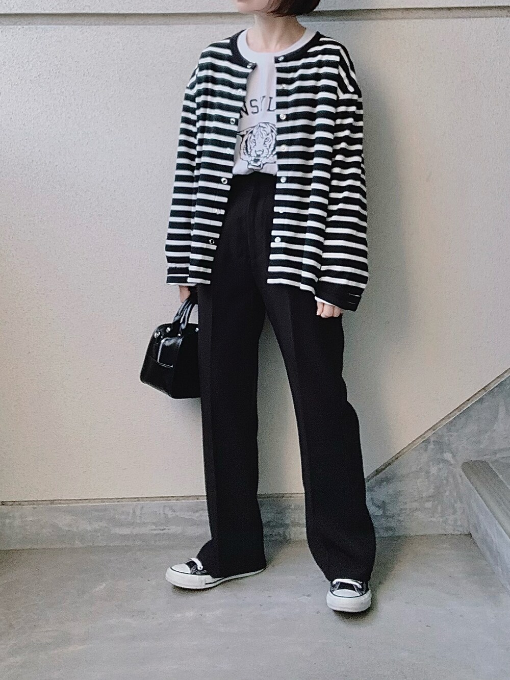 ブラック系のカーディガン/ボレロ、ホワイト系のTシャツ/カットソー、ブラック系のスラックスを着用したレディースの春コーディネートの2枚目の写真