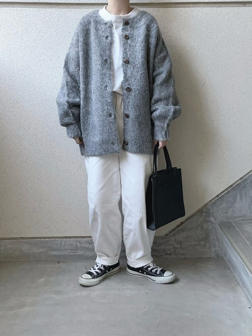 ブラック系のカーディガン/ボレロ、ブラック系のショルダーバッグ、ホワイト系のデニムパンツを着用したレディースの冬コーディネートの2枚目の写真