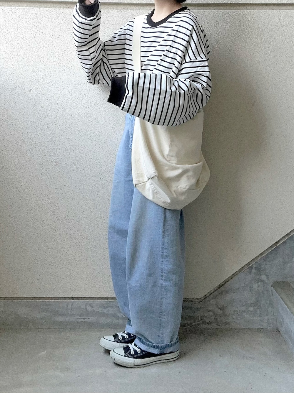 ブラック系のTシャツ/カットソー、ブルー系のデニムパンツ、ホワイト系のショルダーバッグを着用したレディースの春コーディネートの2枚目の写真