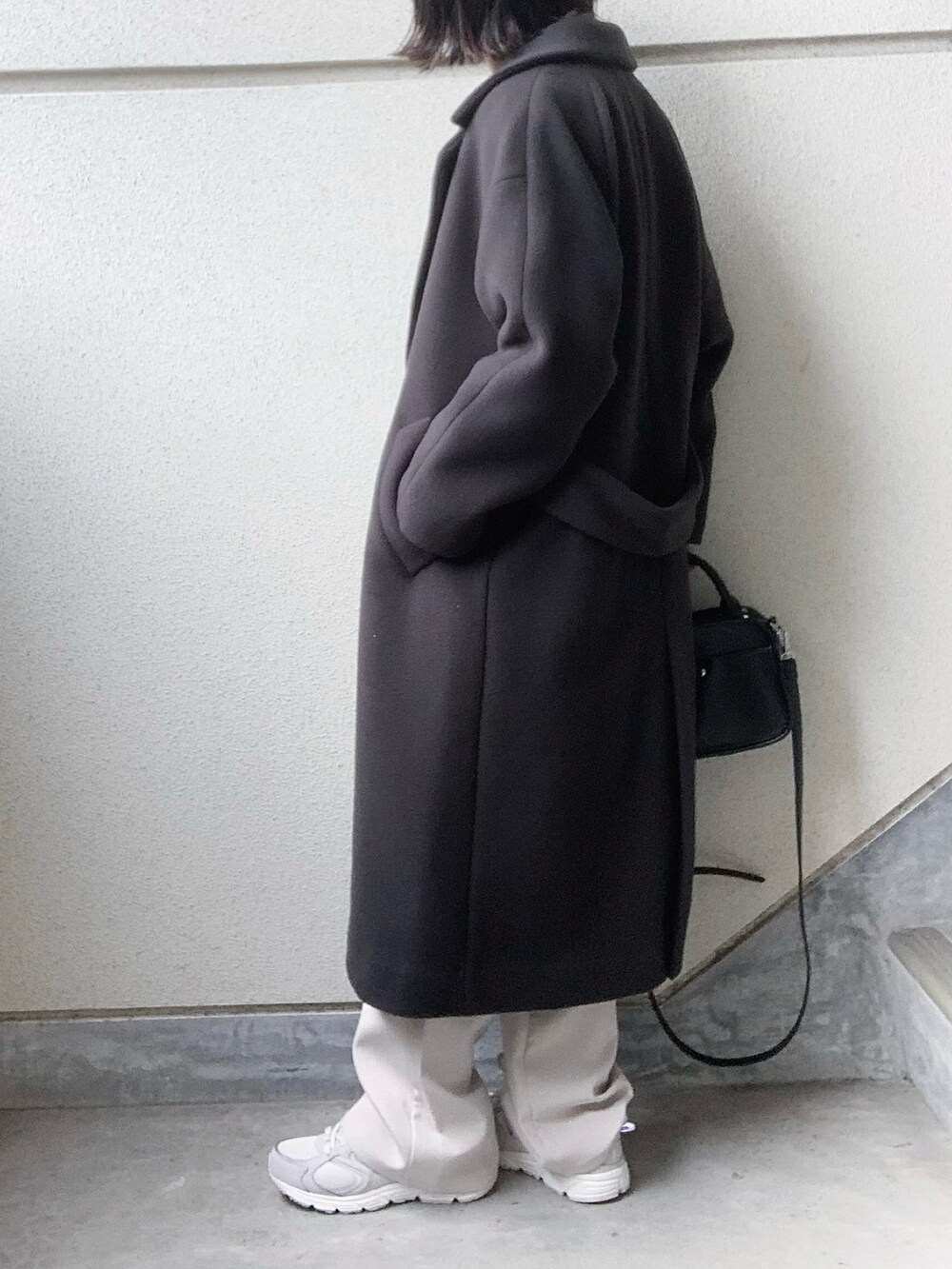 グレー系のチェスターコート、グリーン系のスウェット、グレー系のスニーカーを着用したレディースの秋コーディネートの3枚目の写真