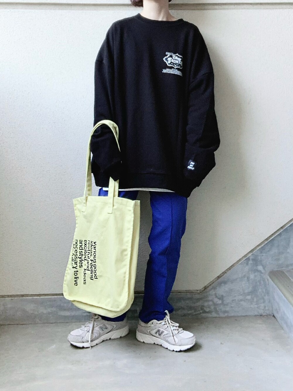ブラック系のスウェット、ブルー系のスウェットパンツ、イエロー系のトートバッグを着用したレディースの春コーディネートの2枚目の写真
