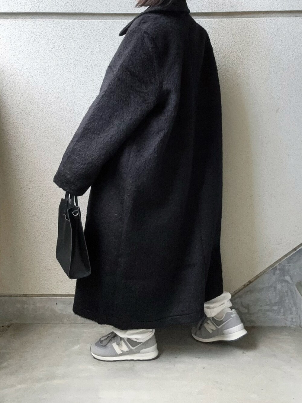 ブラック系のチェスターコート、ブルー系のニット/セーター、ブラック系のショルダーバッグを着用したレディースの秋コーディネートの2枚目の写真