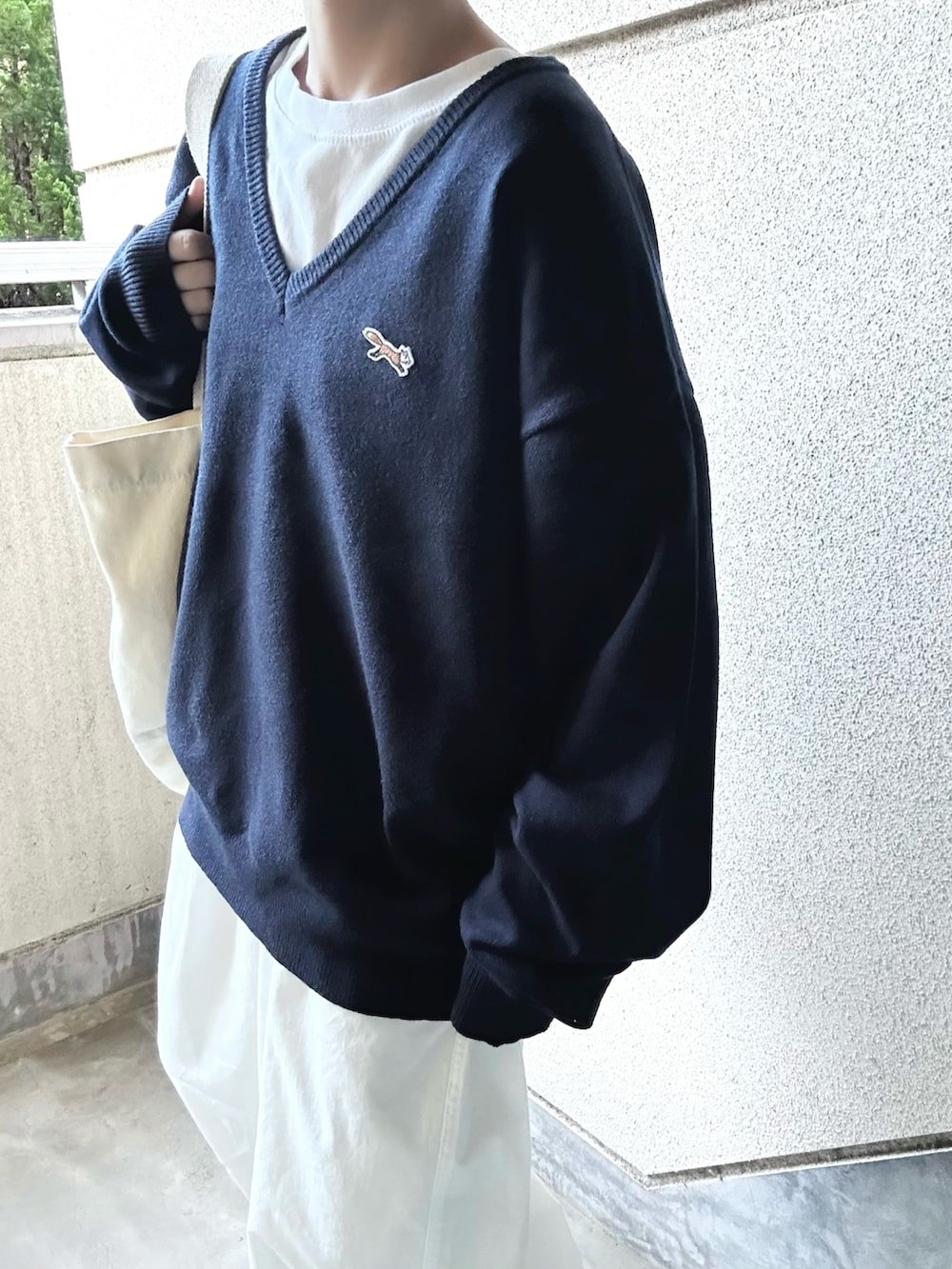 ブルー系のニット/セーター、ホワイト系のチノパンツ、ベージュ系のスニーカーを着用したレディースの秋コーディネートの3枚目の写真