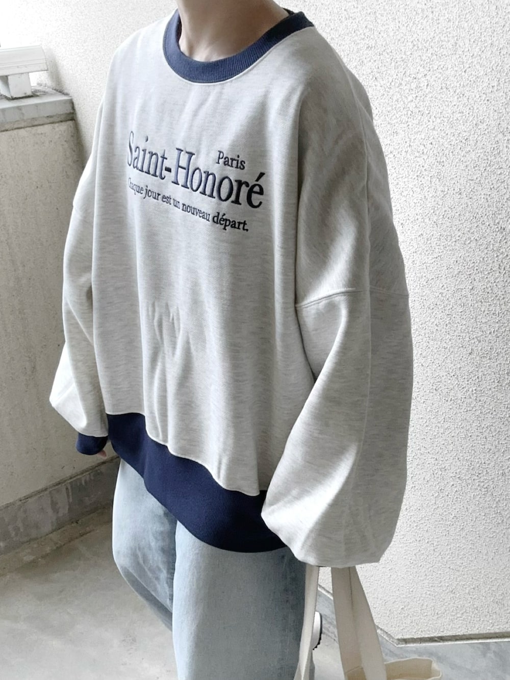 ベージュ系のスウェット、ベージュ系のスニーカー、ブルー系のデニムパンツを着用したレディースの冬コーディネートの3枚目の写真