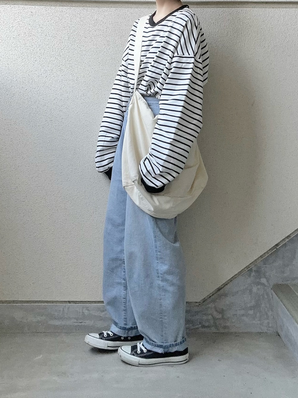 ブラック系のTシャツ/カットソー、ブルー系のデニムパンツ、ホワイト系のショルダーバッグを着用したレディースの春コーディネートの3枚目の写真