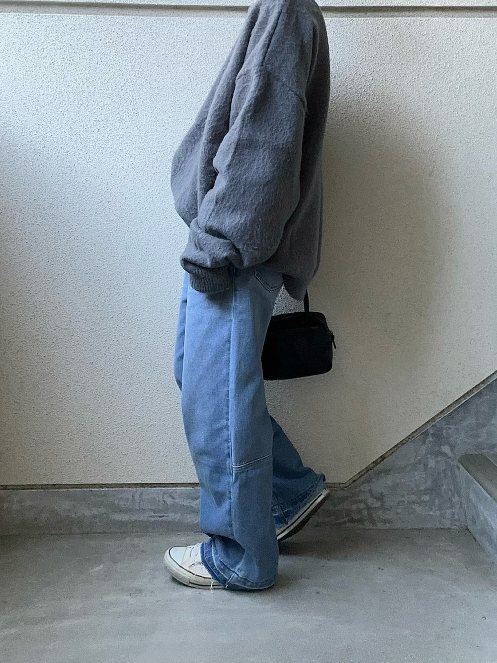グレー系のニット/セーター、ブルー系のデニムパンツ、ブラック系のボストンバッグを着用したレディースの冬コーディネートの4枚目の写真