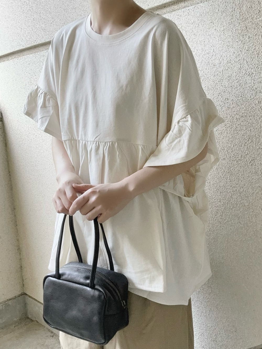 ホワイト系のTシャツ/カットソー、ベージュ系のチノパンツ、ブラック系のボストンバッグを着用したレディースの春コーディネートの4枚目の写真