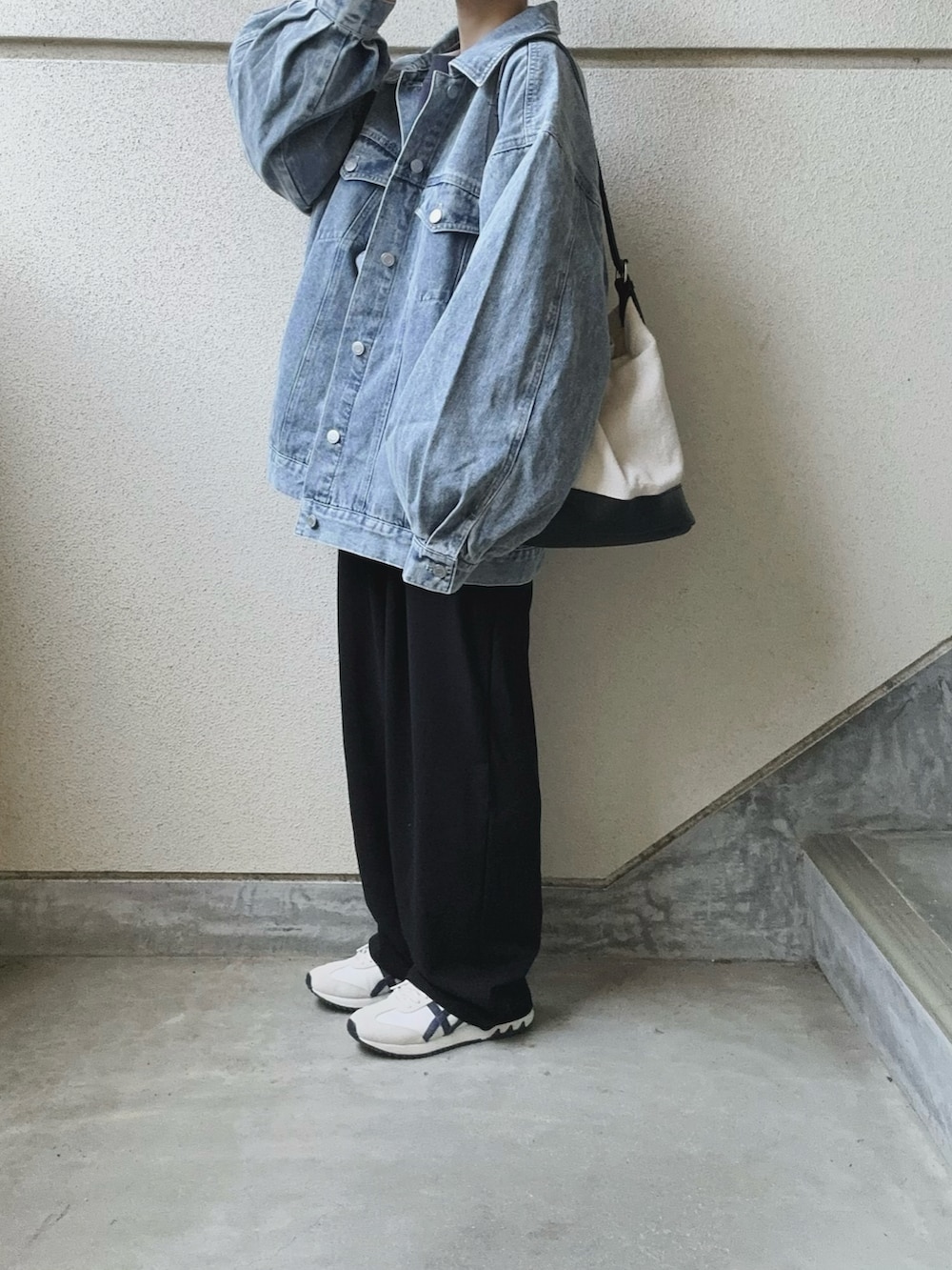 ブラック系のスラックス、ブルー系のデニムジャケット、ブラック系のトートバッグを着用したレディースの春コーディネートの2枚目の写真