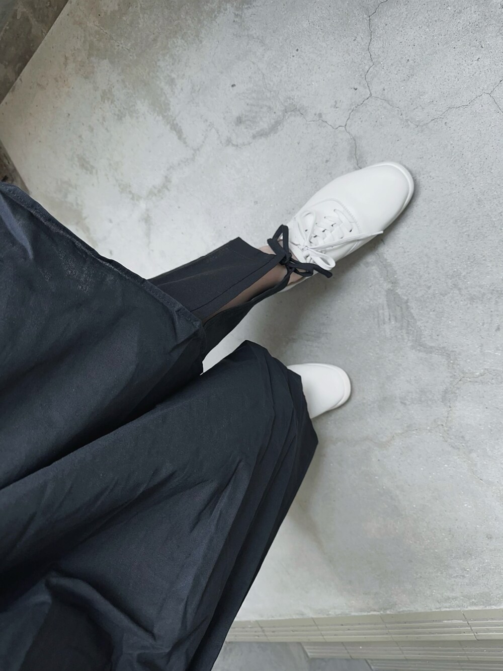 ブラック系のワンピース、ブラック系のスラックス、ホワイト系のスニーカーを着用したレディースの春コーディネートの5枚目の写真