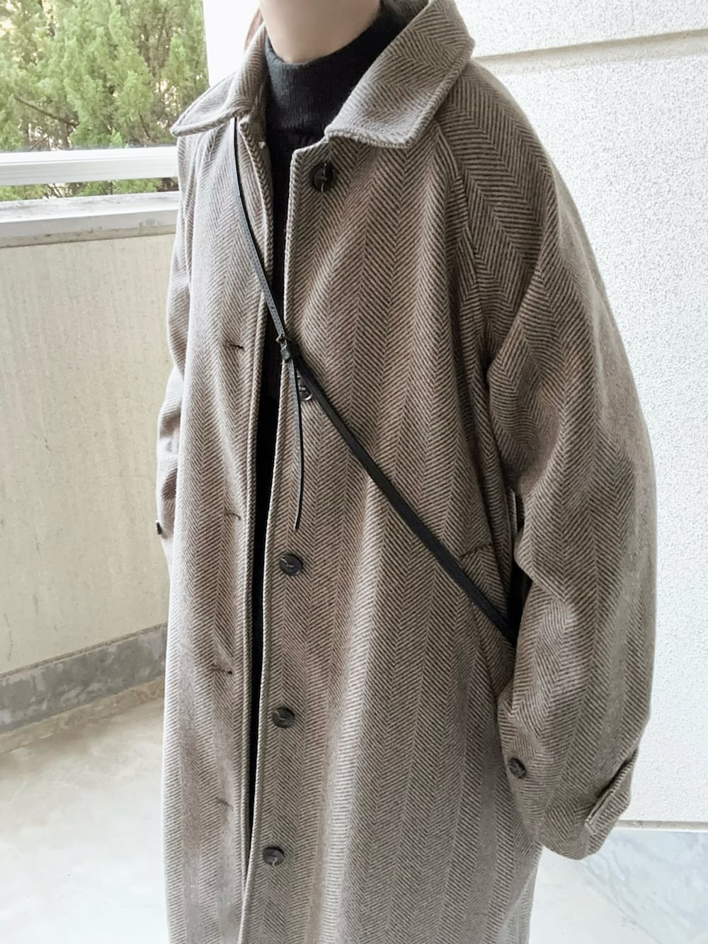 ブラウン系のステンカラーコート、ブルー系のデニムパンツ、ブラック系のショルダーバッグを着用したレディースの冬コーディネートの3枚目の写真