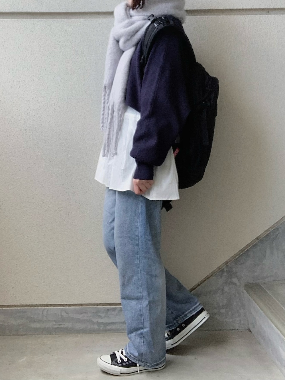 ブルー系のニット/セーター、ブルー系のデニムパンツ、ブラック系のバックパック/リュックを着用したレディースの冬コーディネートの2枚目の写真