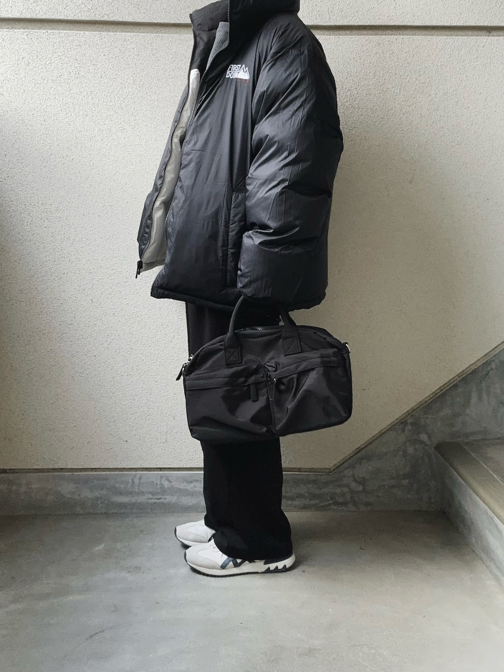 ホワイト系のダウンジャケット/コート、ブラック系のスラックス、グレー系のニット/セーターを着用したレディースの冬コーディネートの2枚目の写真