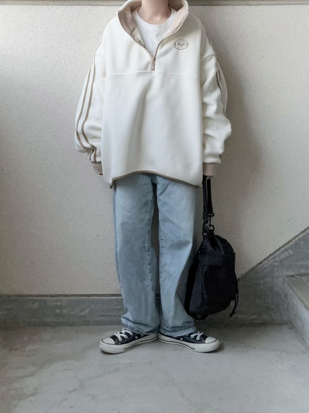 ホワイト系のスウェット、ブラック系のショルダーバッグ、ブルー系のデニムパンツを着用したレディースの秋コーディネートの3枚目の写真