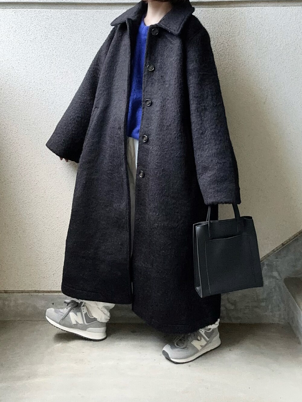 ブラック系のチェスターコート、ブルー系のニット/セーター、ブラック系のショルダーバッグを着用したレディースの秋コーディネートの4枚目の写真