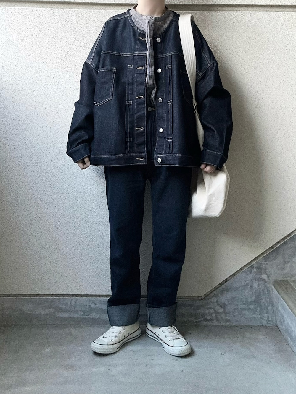 ブルー系のデニムジャケット、グレー系のパーカー、ホワイト系のショルダーバッグを着用したレディースの春コーディネートの4枚目の写真