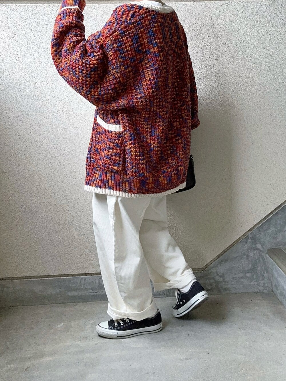 ホワイト系のパンツ、オレンジ系のカーディガン/ボレロ、ホワイト系のTシャツ/カットソーを着用したレディースの冬コーディネートの4枚目の写真