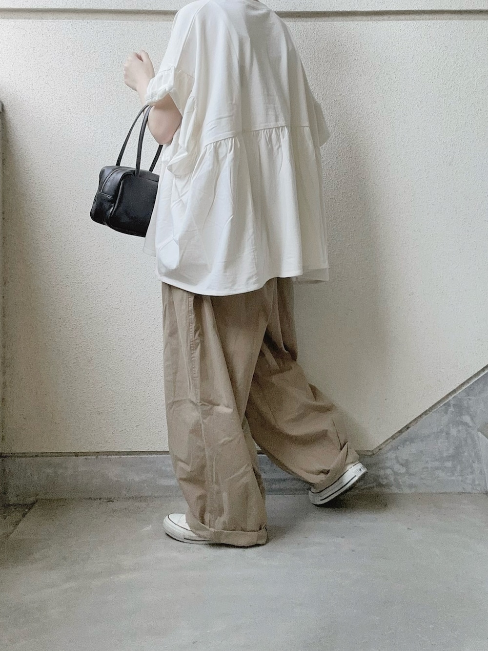 ホワイト系のTシャツ/カットソー、ベージュ系のチノパンツ、ブラック系のボストンバッグを着用したレディースの春コーディネートの3枚目の写真