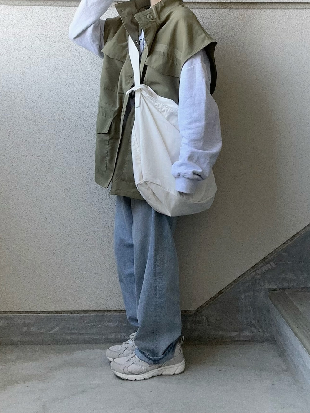 グリーン系のベスト、ブルー系のデニムパンツ、ホワイト系のショルダーバッグを着用したレディースの春コーディネートの3枚目の写真