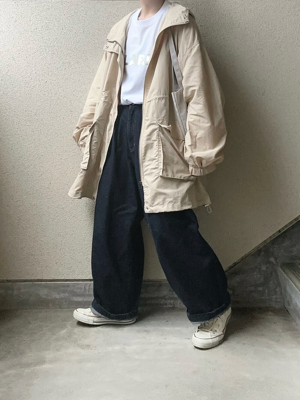 ホワイト系のTシャツ/カットソー、ベージュ系のマウンテンパーカー、ブルー系のデニムパンツを着用したレディースの春コーディネートの2枚目の写真