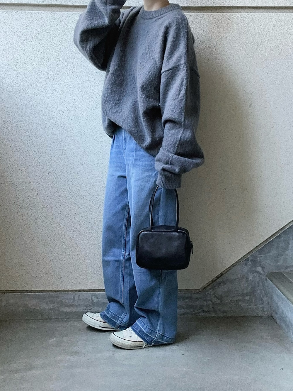 グレー系のニット/セーター、ブルー系のデニムパンツ、ブラック系のボストンバッグを着用したレディースの冬コーディネートの5枚目の写真