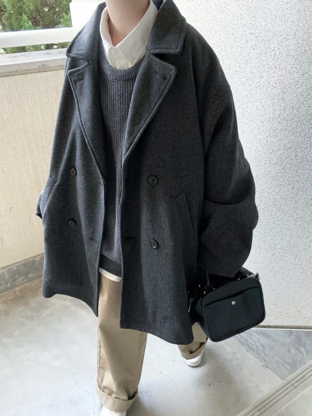 グレー系のピーコート、グレー系のニット/セーター、ホワイト系のシャツ/ブラウスを着用したレディースの冬コーディネートの3枚目の写真