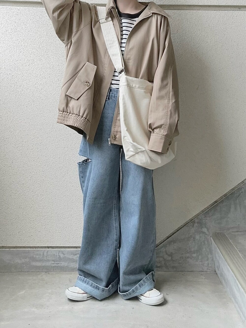 ブルー系のデニムパンツ、ベージュ系のトレンチコート、ブラック系のTシャツ/カットソーを着用したレディースの春コーディネートの4枚目の写真