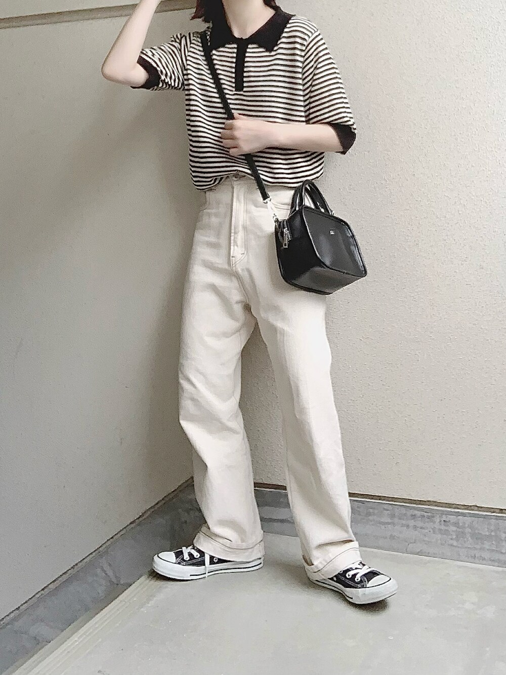 ブラック系のポロシャツ、ホワイト系のデニムパンツを着用したレディースの夏コーディネートの2枚目の写真